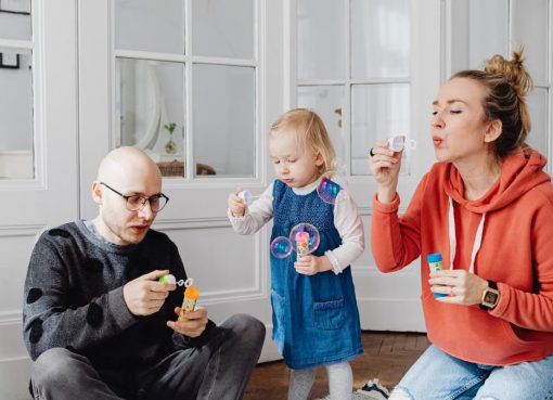 Family enjoying quality time blowing bubbles indoors, capturing joyful moments.